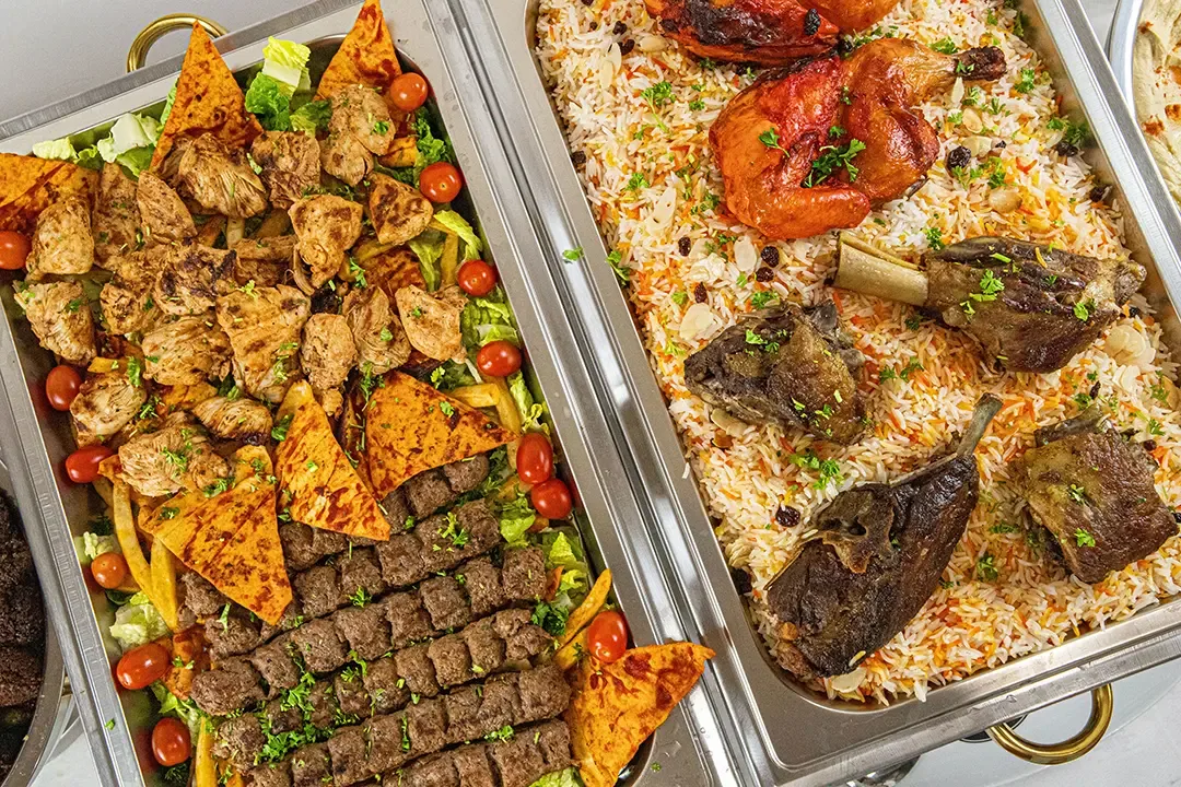 A colorful Malooga catering spread with grilled meats, rice, and chicken
